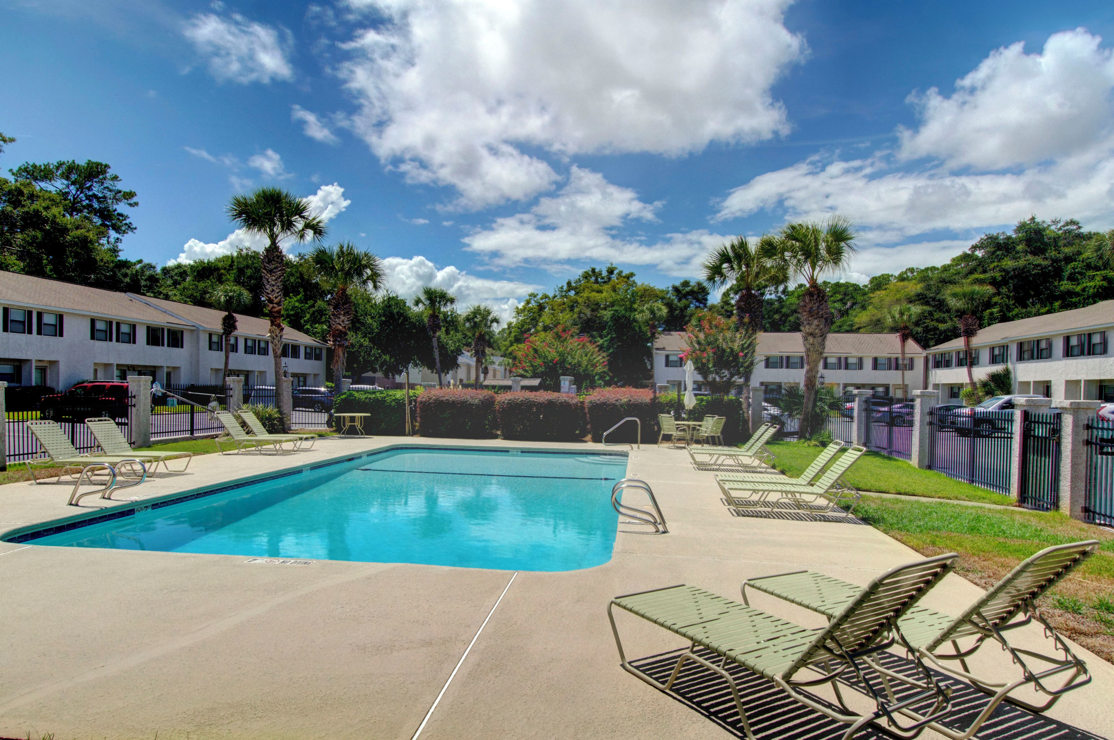A swimming pool with lounge chairs and a clear sky.