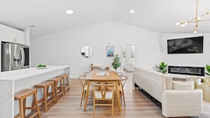 Una cocina moderna con armarios blancos, una mesa de comedor de madera y taburetes de bar.