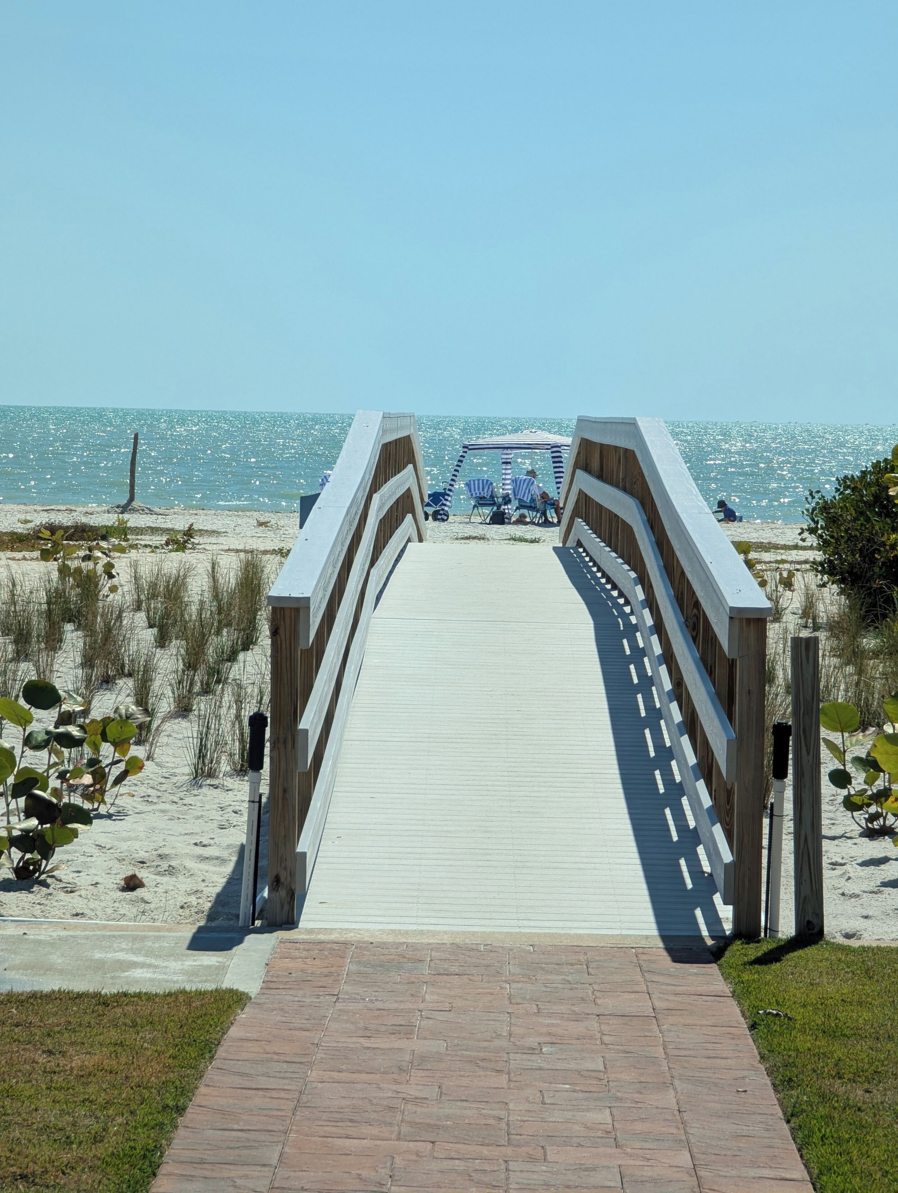Une promenade en bois menant à une plage, avec un espace de repos abrité.