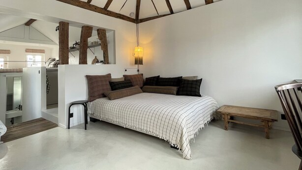 Ein Schlafzimmer mit einem Bett, einer Holzbank, einem Spiegel und einer Hängelampe.