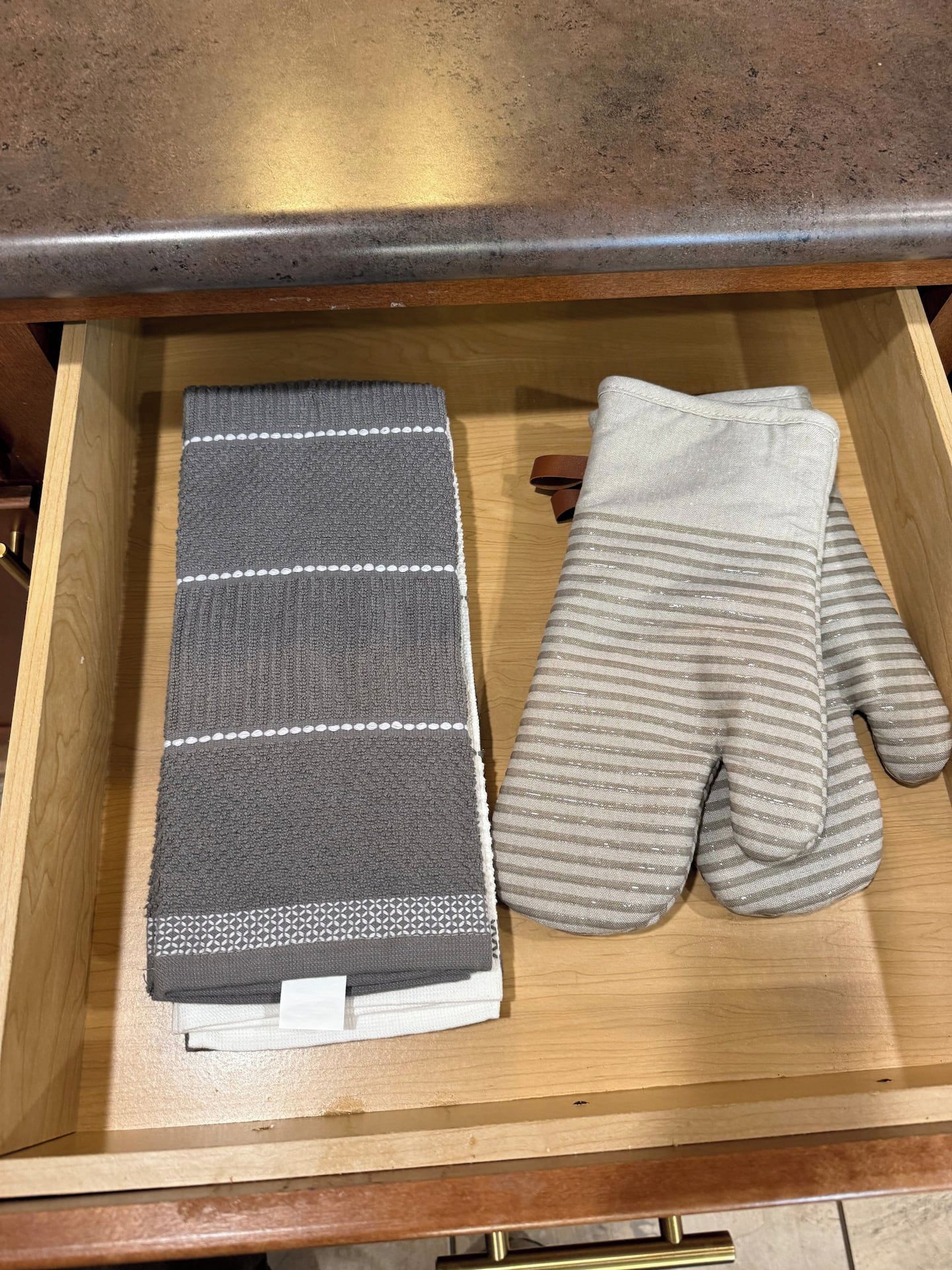 Een lade met een opgevouwen grijs-wit gestreept handdoek en een paar grijs gestreepte sokken.