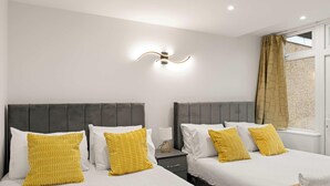 Een hotelkamer met twee bedden, een nachtkastje, een lamp en een raam met gordijnen.