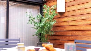Una mesa con cruasanes y una taza, una planta en maceta y una pared de madera.