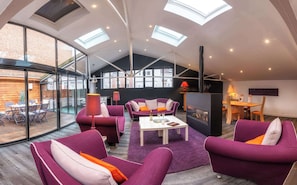 Un salon moderne doté d’un plafond haut, de fenêtres de toit et d’une cheminée.