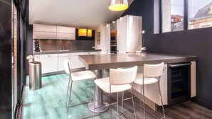 Una cocina moderna con una isla central, taburetes de bar y un ventanal grande.