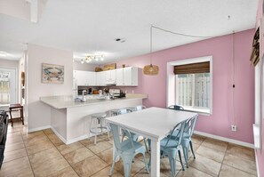 A modern kitchen with white cabinets, a central island, and a dining area with blue chairs. - Emerald Escape 1 - 3 Blocks to Beach (Panama City)