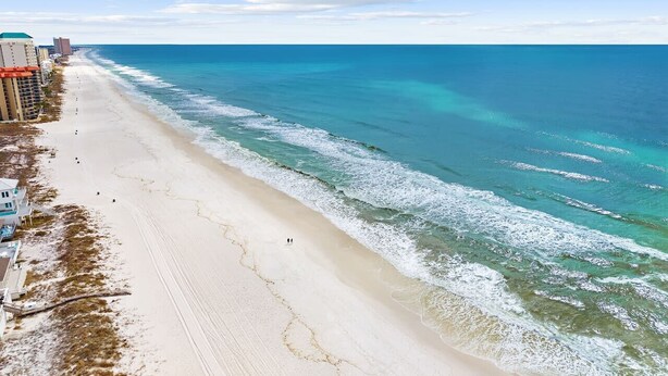 A beach with a clear view of the ocean, a sandy shoreline, and buildings along the coast. - Emerald Escape 1 - 3 Blocks to Beach (Panama City)