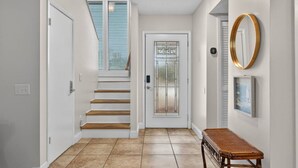 A clean, modern hallway with a wooden staircase, a door with a frosted glass panel, a small table, and a wall-mounted mirror. - Emerald Escape 1 - 3 Blocks to Beach (Panama City)