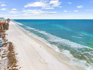Ein Strand mit freiem Blick auf den Ozean, einem sandigen Ufer und Gebäuden entlang der Küste.