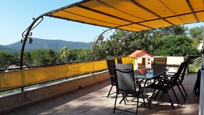 A covered outdoor patio with a table and chairs, overlooking a scenic landscape with trees and mountains. - 3-bedroom villa with exclusive pool (Garéoult)