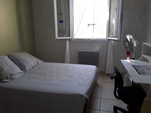 A bedroom with a bed, a desk, a chair, a window, and a radiator. - 3-bedroom villa with exclusive pool (Garéoult)