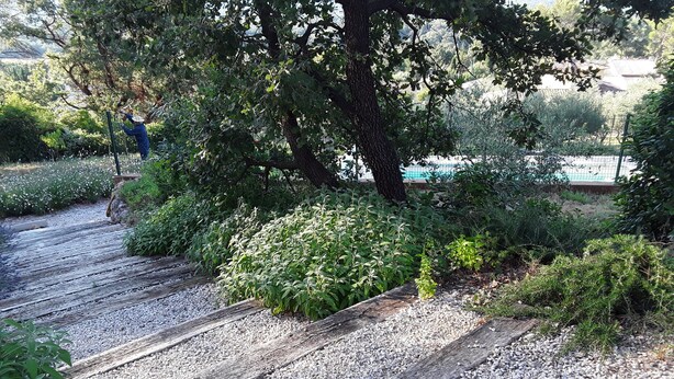 A wooden pathway with gravel, surrounded by greenery and trees. - 3-bedroom villa with exclusive pool (Garéoult)
