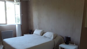 A bedroom with a large bed, two bedside tables, a window, and a radiator. - 3-bedroom villa with exclusive pool (Garéoult)