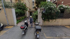 Une rue étroite, bordée de scooters garés, où se promène un piéton.