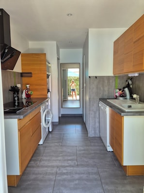 A modern kitchen with wooden cabinets, a dishwasher, and a countertop with various appliances. - 2-4 person 2* cottage in sought-after neighborhood (Sanary-sur-Mer)