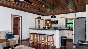 A modern kitchen with wooden bar stools, a central island, and a refrigerator.