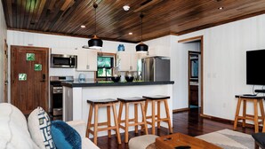 A modern kitchen with wooden stools, a microwave, and a refrigerator.