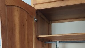 Un meuble en bois avec une étagère et une porte.