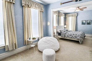 A bedroom with a bed, a round white bean bag, a small bedside table, and a ceiling fan. - Mainstay in Elk Rapids, splendid views and comfort (Elk Rapids)