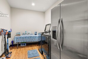 Une petite cuisine équipée avec un réfrigérateur en acier inoxydable, une table avec des produits de nettoyage et un aspirateur.