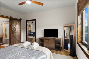 A bedroom with a bed, a television, a mirror, and a ceiling fan. - Wine Country Latitude. Northern Michigan Attitude (Suttons Bay)