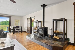 A spacious living room with a fireplace, a dining area, and a view of a green landscape. - Wine Country Latitude. Northern Michigan Attitude (Suttons Bay)