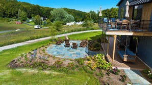 A deck with outdoor seating and a stone patio. - Wine Country Latitude. Northern Michigan Attitude (Suttons Bay)