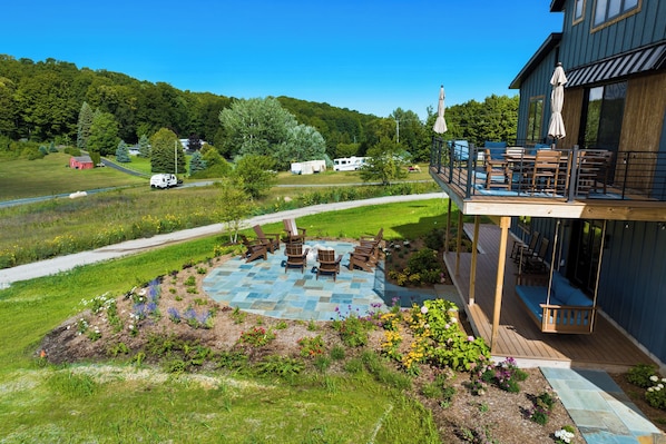 A deck with outdoor seating and a stone patio. - Wine Country Latitude. Northern Michigan Attitude (Suttons Bay)