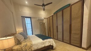 A bedroom with a bed, a nightstand, a lamp, a ceiling fan, a window with curtains, and a wardrobe. - Playa La Ropa 
Brand new Villa with 7-minute walk to the beach (Zihuatanejo)