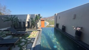 A private pool area with lounge chairs, potted plants, and a view of a coastal landscape. - Playa La Ropa 
Brand new Villa with 7-minute walk to the beach (Zihuatanejo)