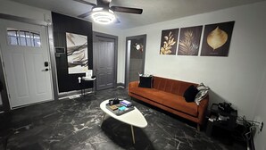 Een moderne woonkamer met een marmeren vloer, een plafondventilator, een bank en kunstwerken aan de muur.
