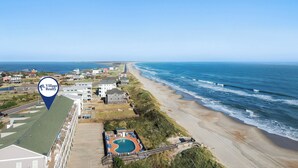 A coastal property with a swimming pool, beach access, and a view of the ocean.