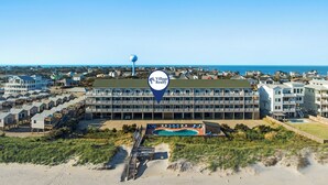A coastal hotel with multiple stories, a swimming pool, and a beach view.