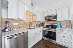 A modern kitchen with white cabinetry, stainless steel appliances, and a tiled backsplash. - 💎Beachfront Luxury 1 BR Condo | 2 Resort Pools | Seaside Beach & Racquet 3205 (Orange Beach)