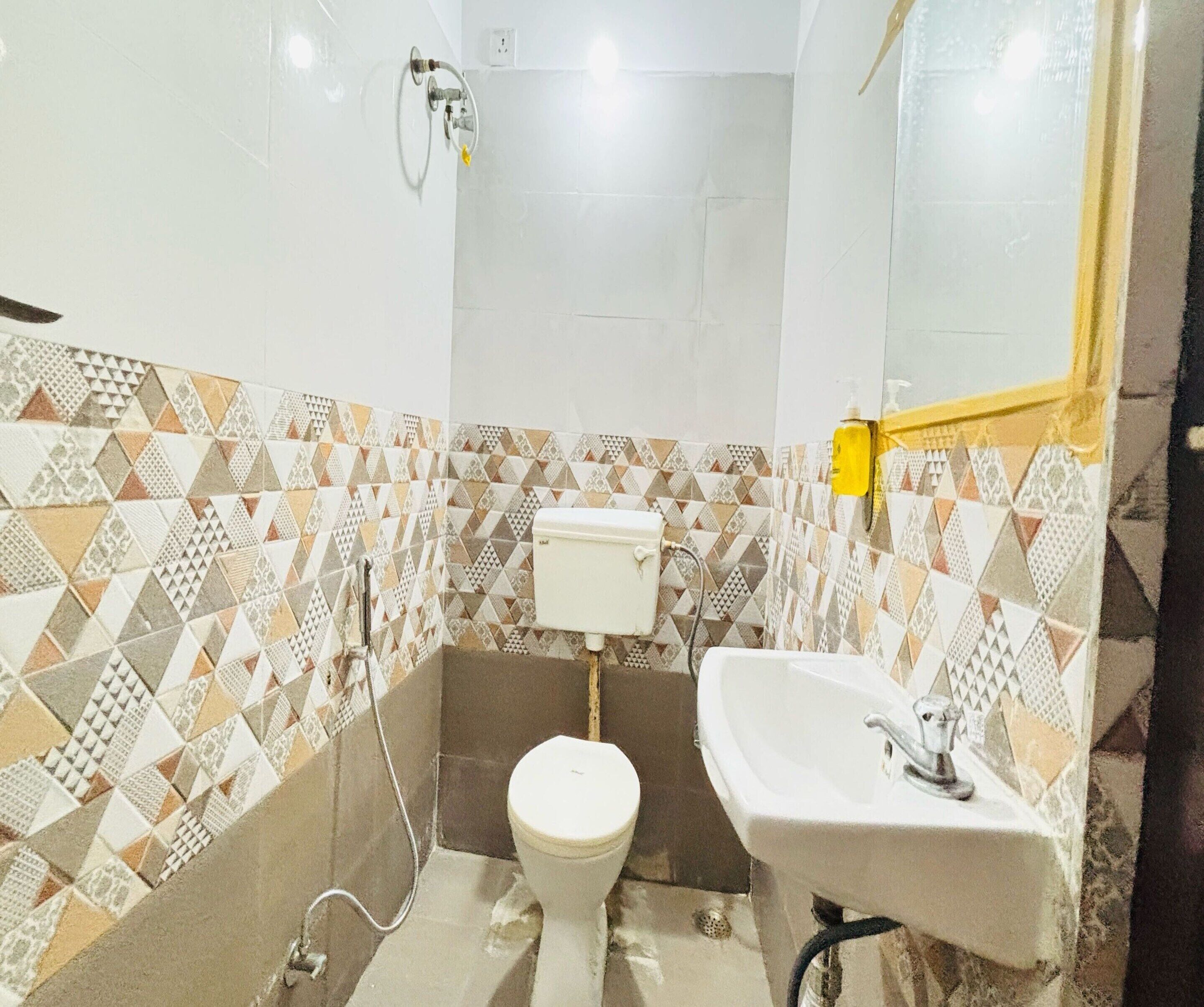 A bathroom with a toilet, sink, and shower. The walls have a geometric tile pattern.