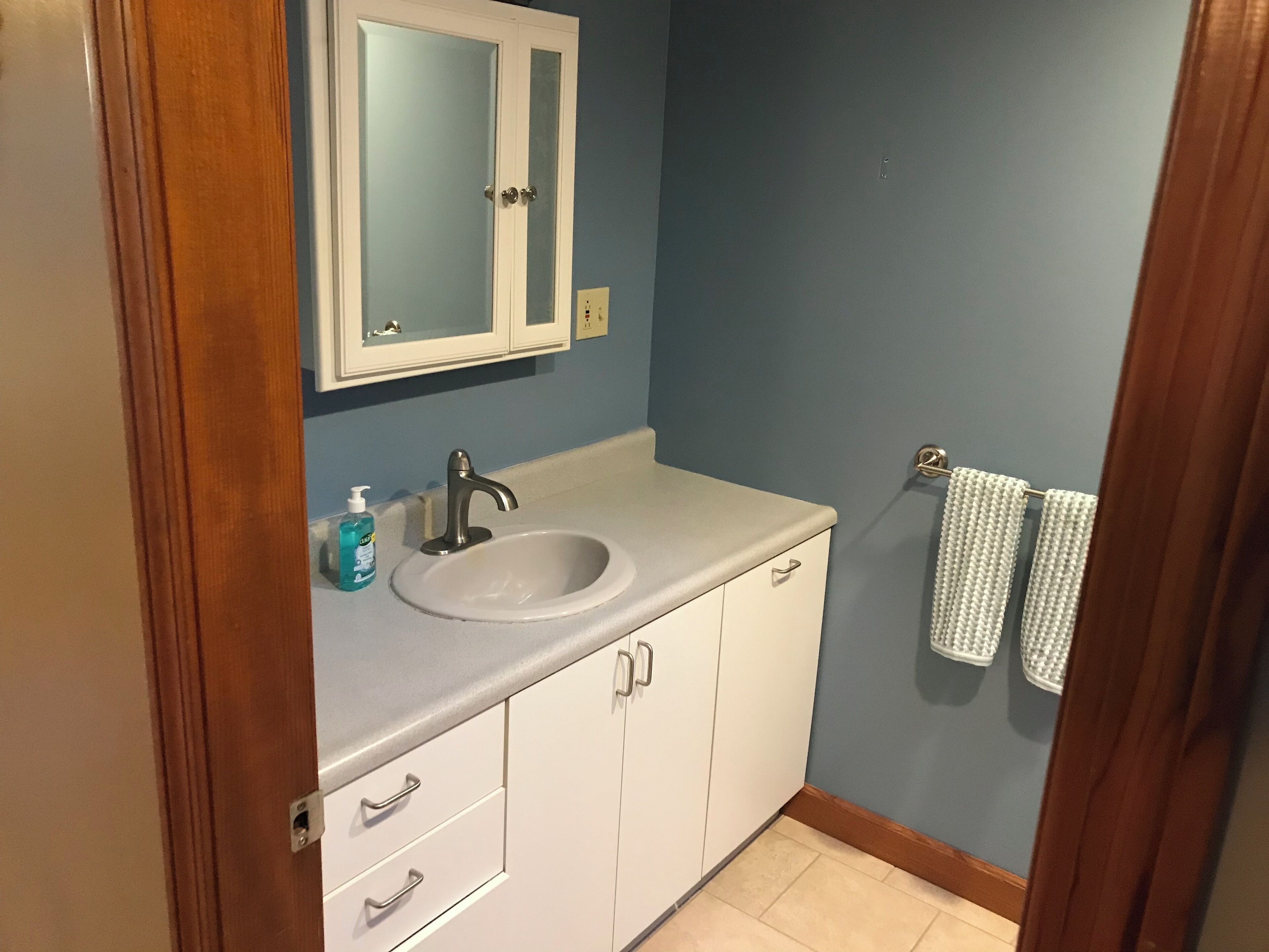 A bathroom with a white sink, a mirror, and a towel rack.