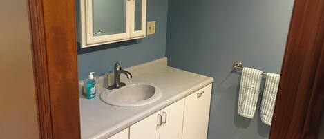 A bathroom with a white sink, a mirror, and a towel rack.