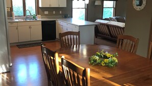 Una cocina moderna con armarios blancos, una mesa de comedor de madera y una isla central.