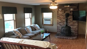 Una sala de estar acogedora con un sofá, una mesa de centro, una chimenea y un televisor montado en la pared.