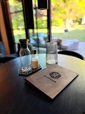 A table with a menu, a candle, and a glass bottle. - Goodwood Lodge am See - Holiday home with sauna (Scharbeutz)