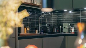 Eine moderne Küche mit schwarzem Fliesenrückwand, Edelstahlgeräten und verschiedenen Küchenutensilien auf der Arbeitsfläche.
