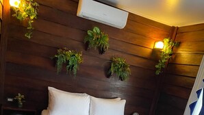 Una cama bien hecha con una toalla, paredes de madera y plantas en la pared.