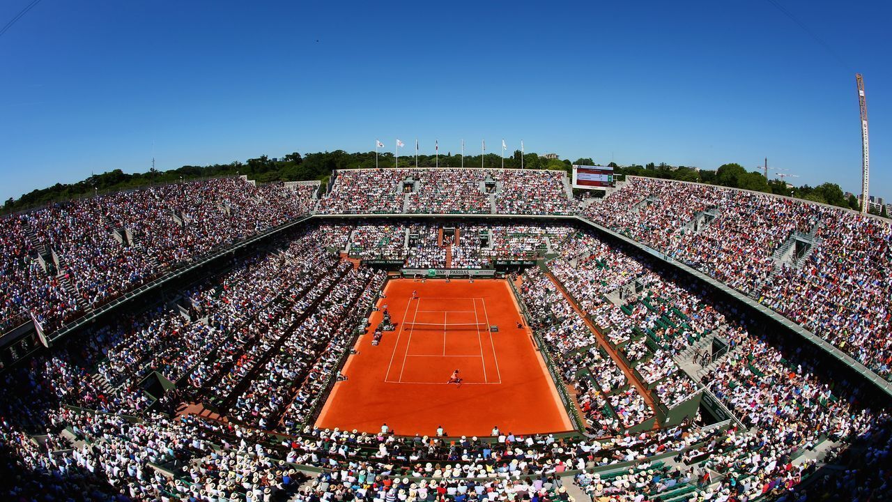 Un grand stade de tennis couvert, doté de plusieurs niveaux de gradins et d’un court central.