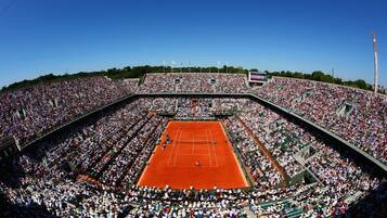 Un grand stade de tennis couvert, doté de plusieurs niveaux de gradins et d’un court central.