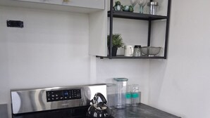 Cocina con estufa a gas, horno y un mueble blanco superior.