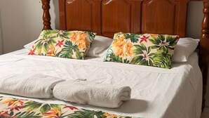 A neatly made bed with floral-patterned pillows and a white towel.