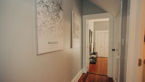 A hallway with wooden flooring, a rug, and framed maps on the wall. - Modern One bedroom near downtown and Augusta National (Augusta)