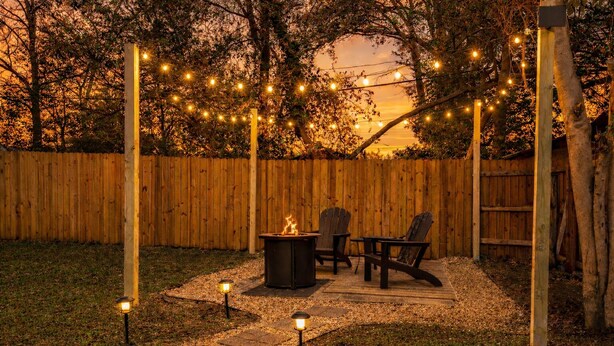 An outdoor patio area with a fire pit, two Adirondack chairs, and string lights. - Modern One bedroom near downtown and Augusta National (Augusta)