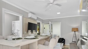 Een moderne keuken met een bar, een eettafel voor vier personen en een bank in de woonkamer.
