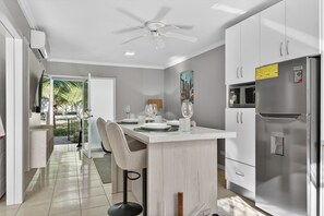 A modern kitchen with a central island, white cabinets, a stainless steel refrigerator, and a ceiling fan. - Modern Condo w / Pool in Playa Coco (Coco)